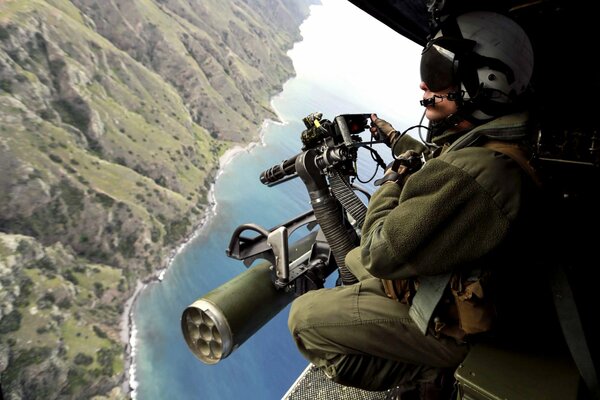 A soldier with a machine gun in a helicopter in the air