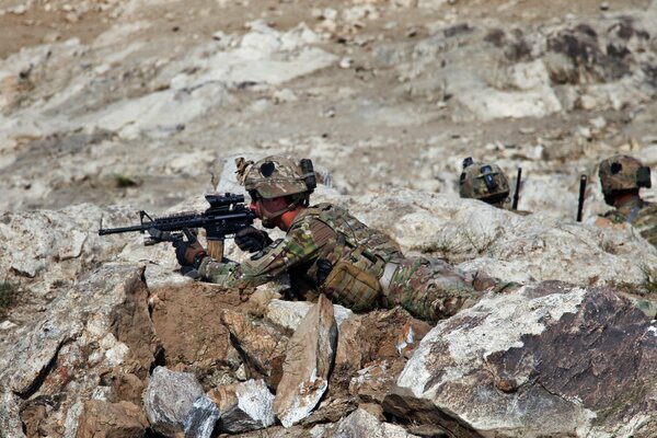 Soldado estadounidense se acuesta y Mira a la vista en las rocas