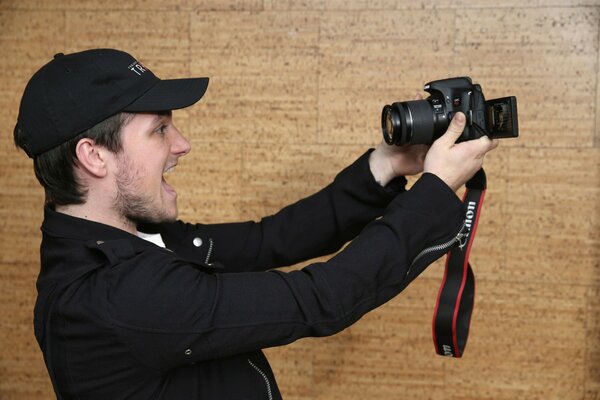 A guy in a black cap takes pictures of himself