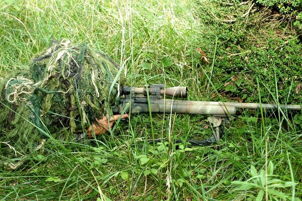 Sniper in camouflage on the green grass