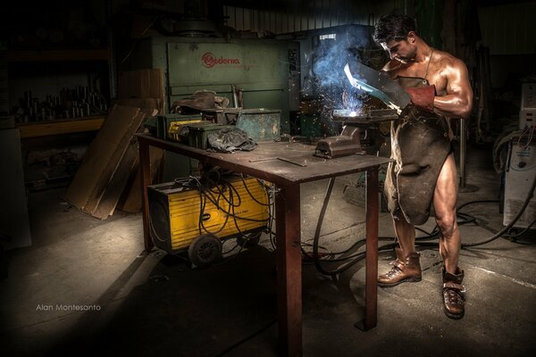 A beautiful naked man with a welding machine