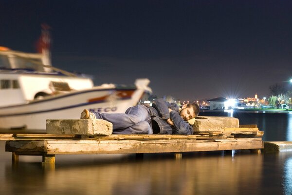 Situation d un homme dormant dans un port sur des rochers