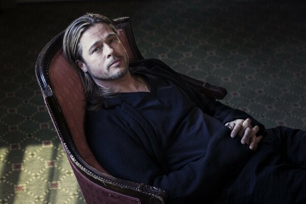 Brad Pitt con ojos tristes descansa en una silla