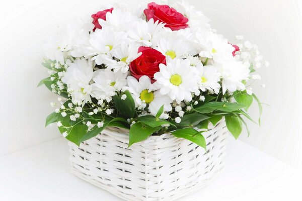 Bouquet of white daisies and red roses in a basket