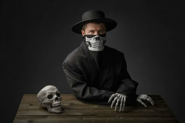 Homme en costume noir à la table avec un crâne