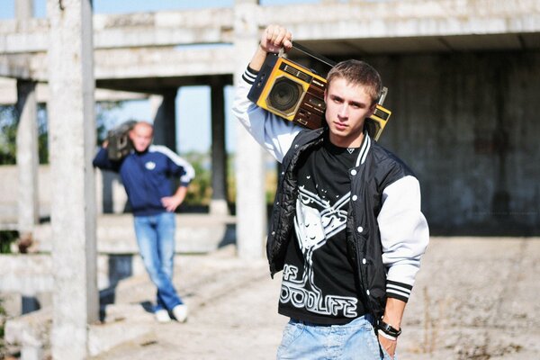 A fashionable young man walks with a tape recorder on his shoulder