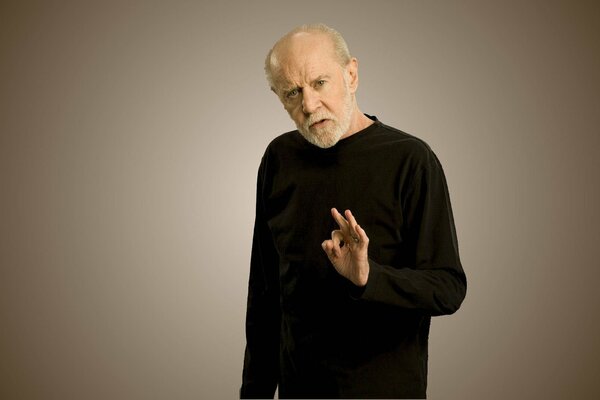 Atheist George Carlin poses in front of a camera