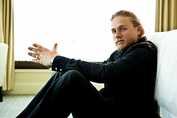 Charlie Hunnam sits on the floor and looks at the camera