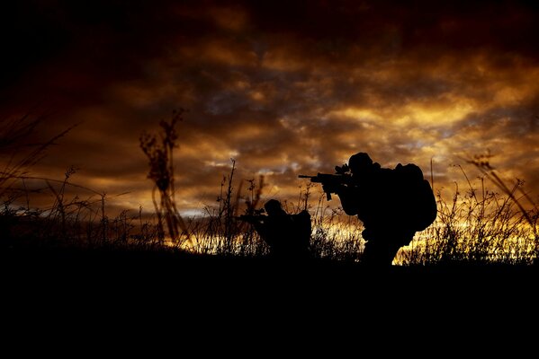 Silhouette of a soldier with a gun in the evening