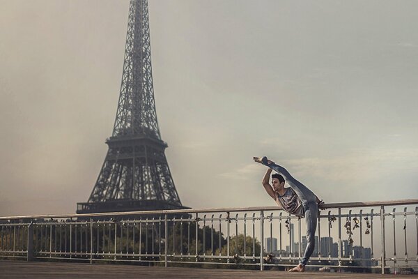 A balleroon does a stretch against the backdrop of the Eiffel Tower