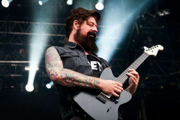 A bearded guitarist is playing on stage