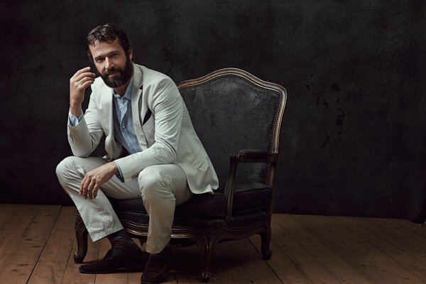 James Purefoy w białym garniturze siedzi na krześle