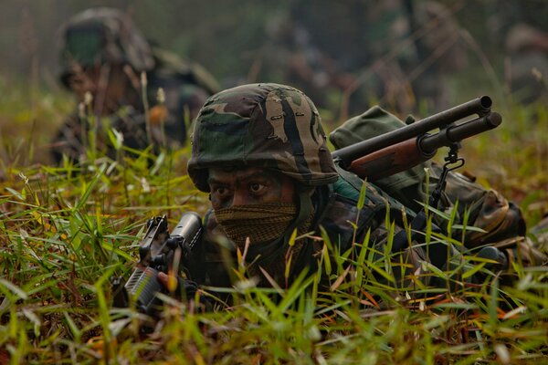 Soldaten mit Waffen verkleideten sich im Gras