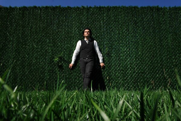 A green wall and a man stands