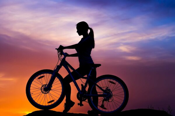 Fille au coucher du soleil. Cyclisme