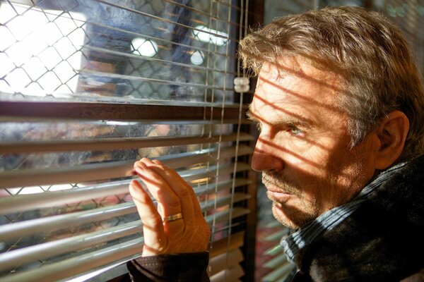 Kevin Costner holds onto the blinds