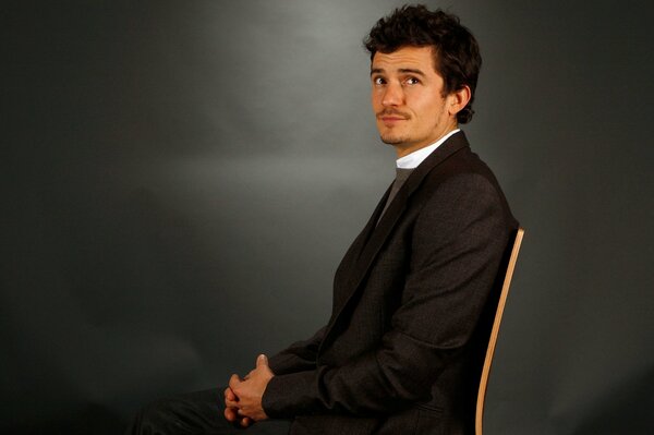 Portrait of Orlando bloom sitting on a chair in a jacket