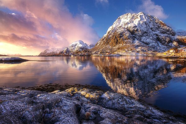 Le coucher de soleil rose et les rochers enneigés se reflètent dans l eau bleue