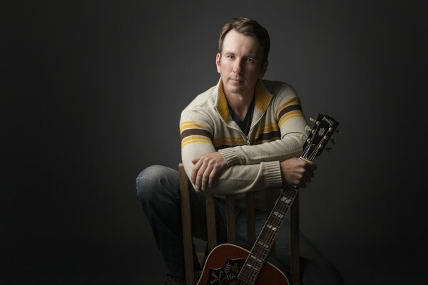 Jason Burton with a guitar on a chair