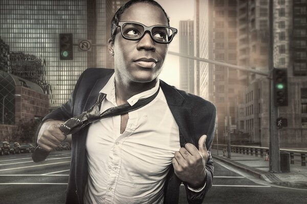 In the city, a guy is walking on the street wearing glasses, a suit and a tie