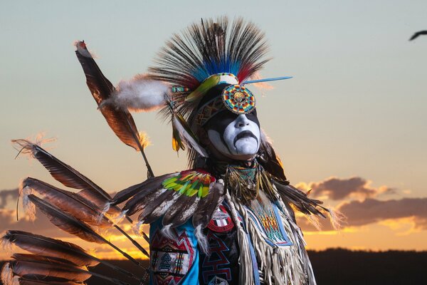 A man in a national costume on the background of sunset