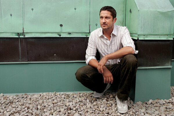 Gerard Butler is sitting and resting on the set tired decided to rest