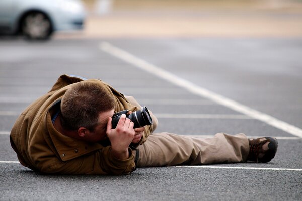 A man takes pictures in a lying position