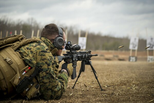 Un uomo in uniforme militare con una pistola giace a terra