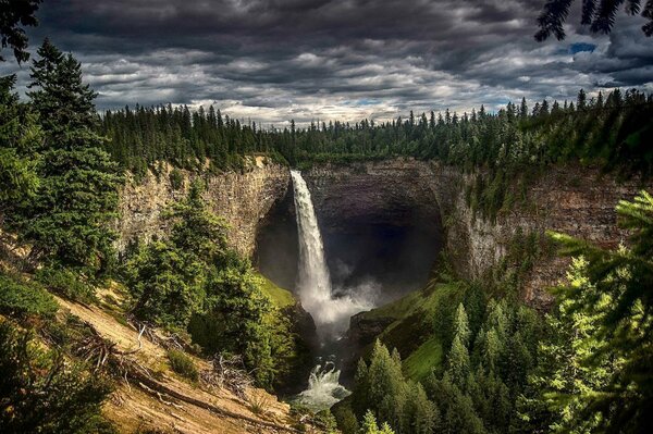 Bewölkter Himmel. Wasserfall unter den Felsen