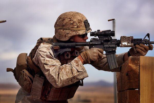 A warrior in camouflage shoots accurately from a machine gun