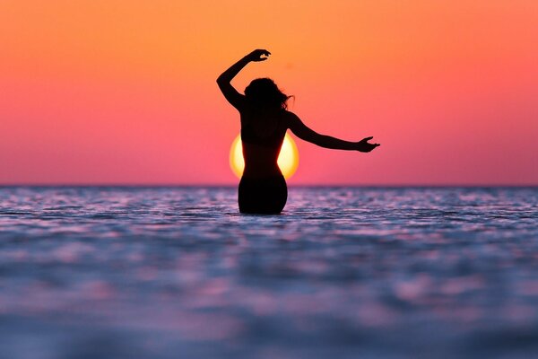 Silhouette eines Mädchens am Meer bei Sonnenuntergang