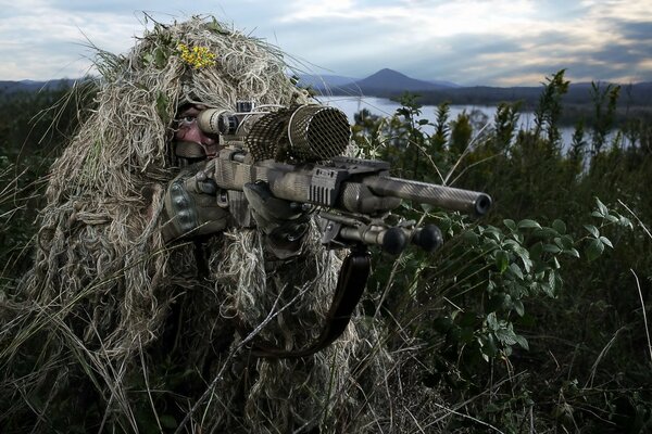 Francotirador en la hierba apunta con un arma