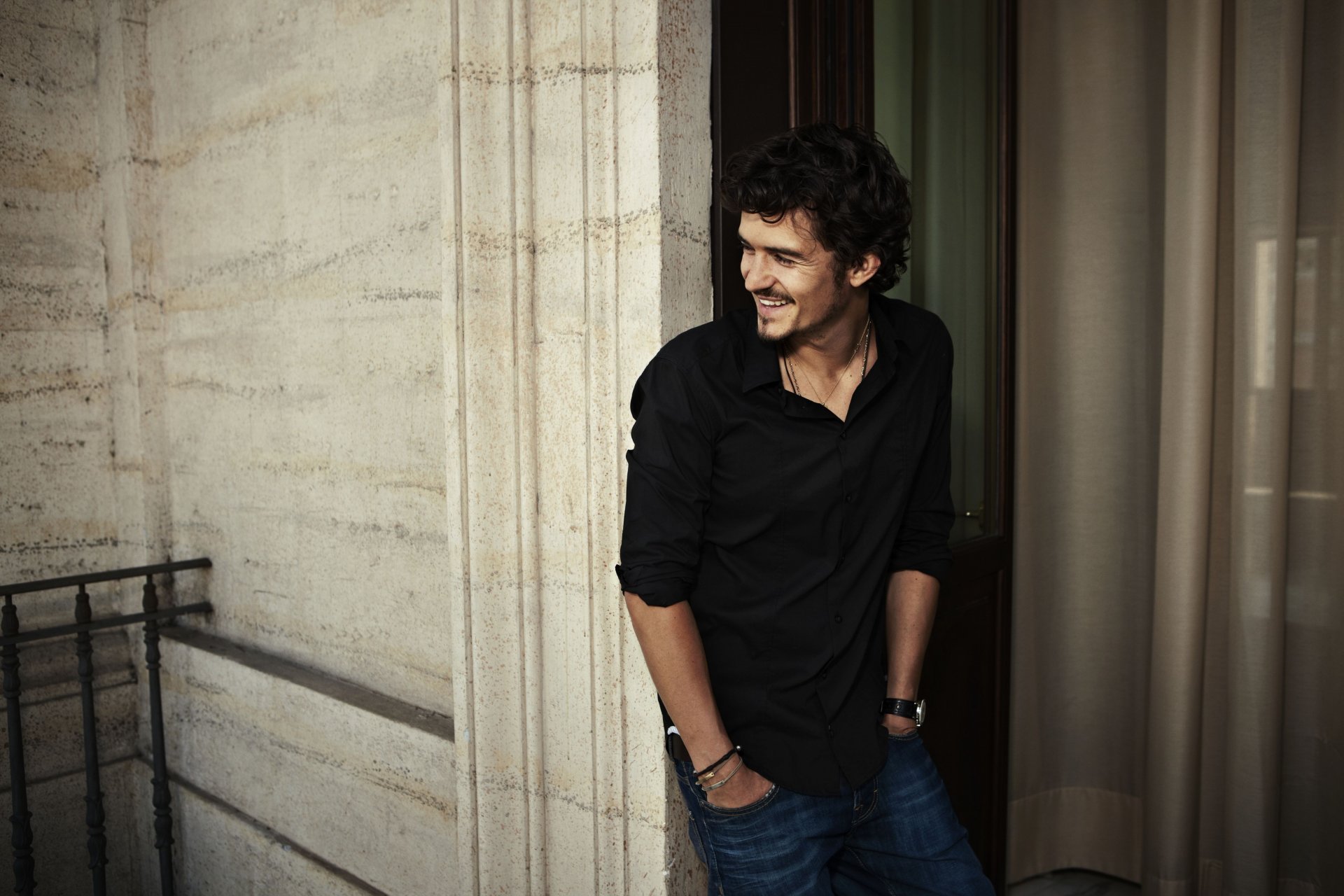 orlando bloom acteur homme célébrité brunet sourire chemise noir jeans balcon