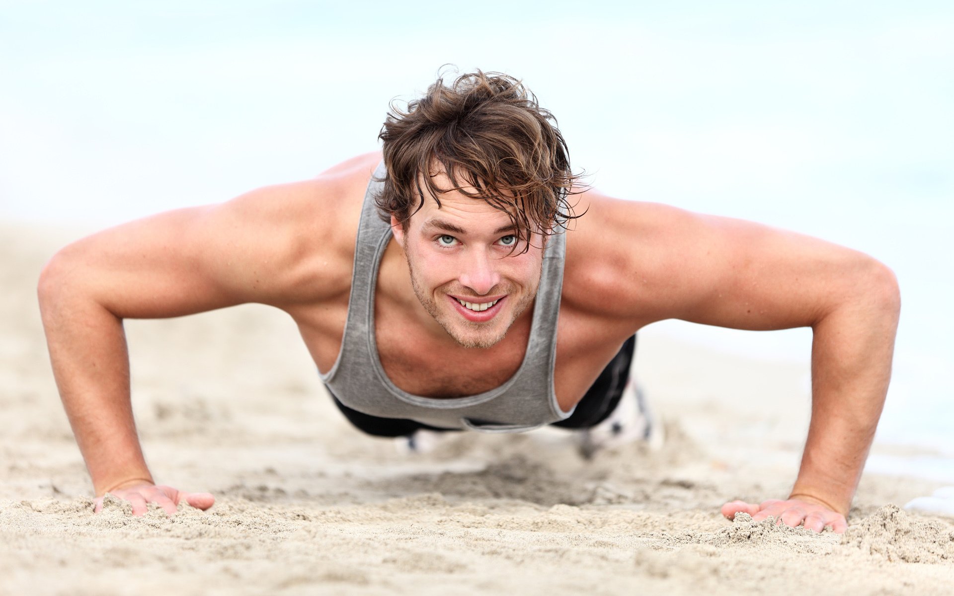 men pushed muscles smile beach sand