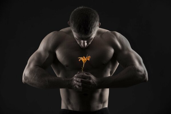 Un homme avec des muscles gonflés tient un lis