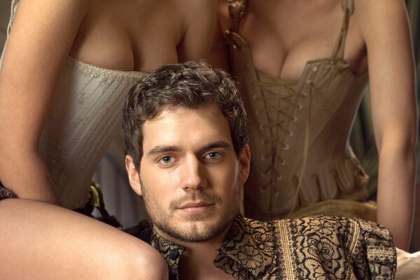 Der Schauspieler der tudor-Serie, henry cavill, und zwei damen in Korsetts