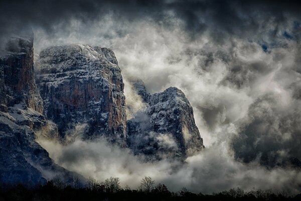 Hohe Berge im Nebel und in den Wolken in der Nacht