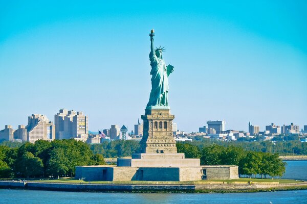 La estatua de la libertad se encuentra majestuosamente en el fondo de la ciudad