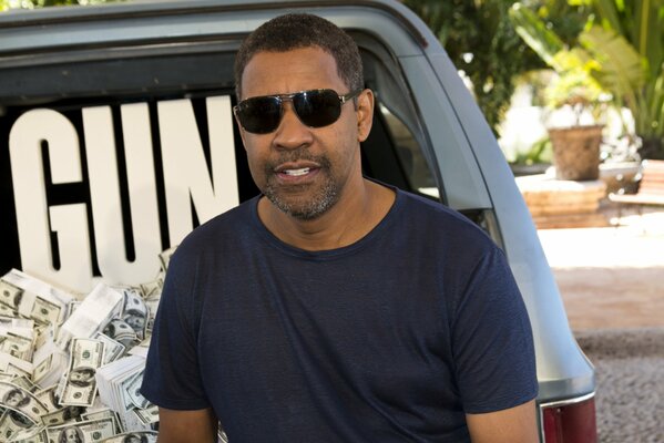 Actor Denzel Washington in black glasses on the background of a car