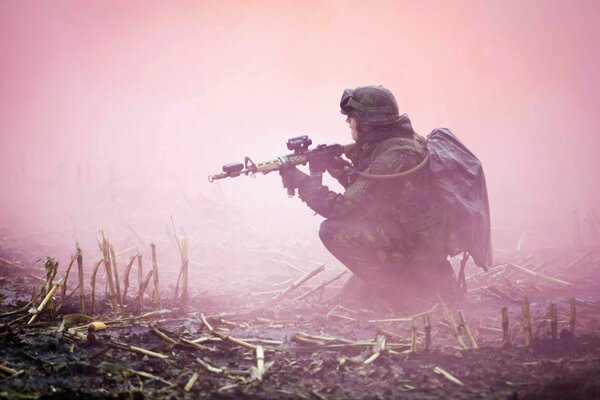 Soldat mit Waffen im Nebel im Feld