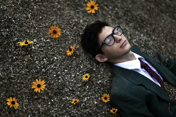 Homme couché dans les pierres avec des fleurs orange