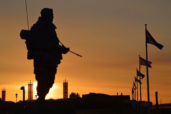 Silhouette eines Militärs mit einer Waffe bei Sonnenuntergang