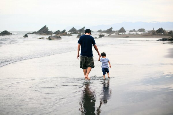 A man s walk with his son s back on the seashore