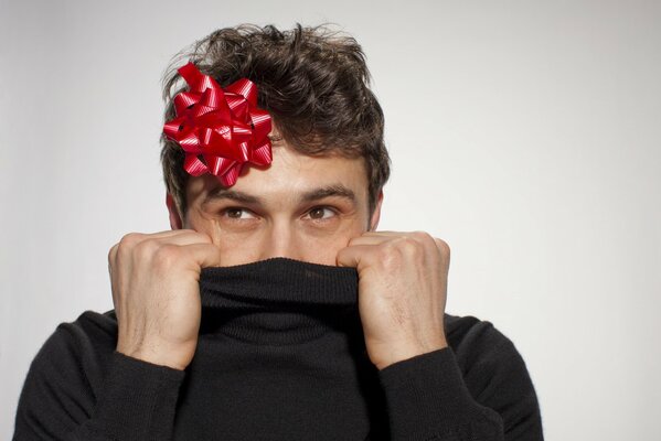 Actor James Franco in a black turtleneck with a red bow on his head