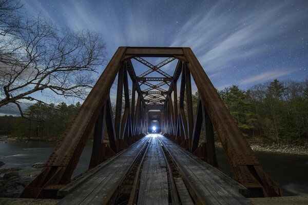 An approaching train in the night over the river