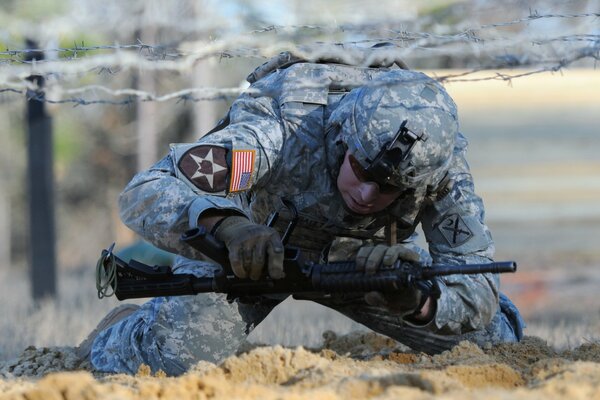 A soldier with a gun climbs through an obstacle course