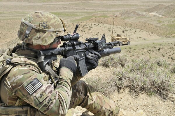 A sniper in khaki takes aim in the mountains