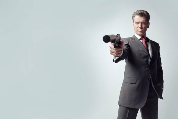 A man in a classic suit with a gun