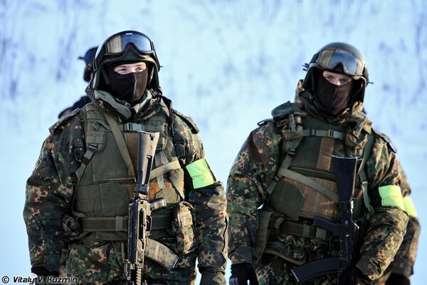 Fuerzas especiales en camuflaje y máscaras con armas en el día de invierno