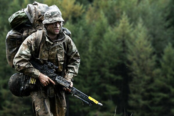 Soldado con armas en el fondo del bosque